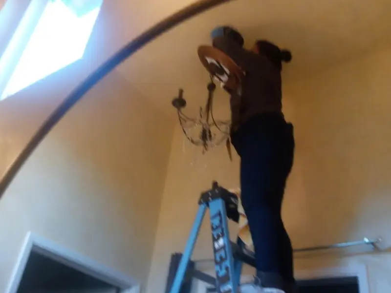 Electrician installing a chandelier in a Kingman residence